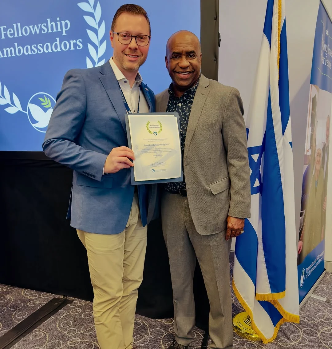 Bruno Portigliatti receiving the IFCJ Ambassador certificate beside the flag of Israel